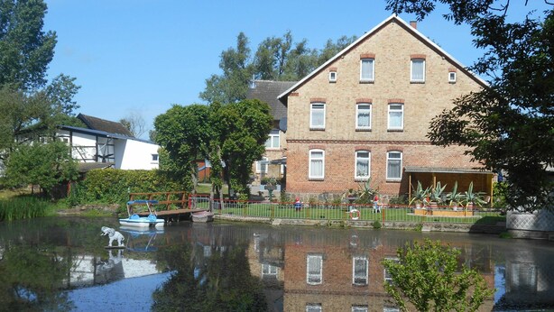 Ein Gebäude aus Ziegelsteinen mit vielen Fenstern und Spiegelung im Wasser.