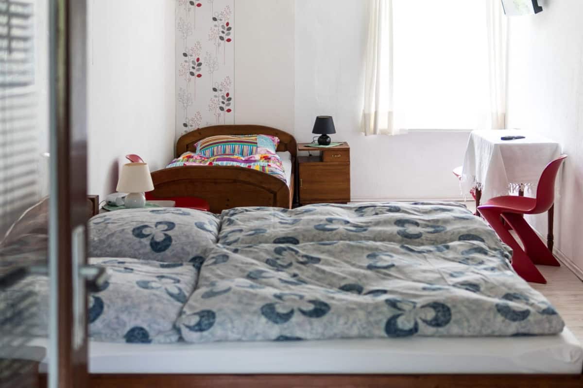 Ein Schlafzimmer mit einem Bett, einem Nachttisch, einer Lampe und einem kleinen Tisch mit einem Stuhl.