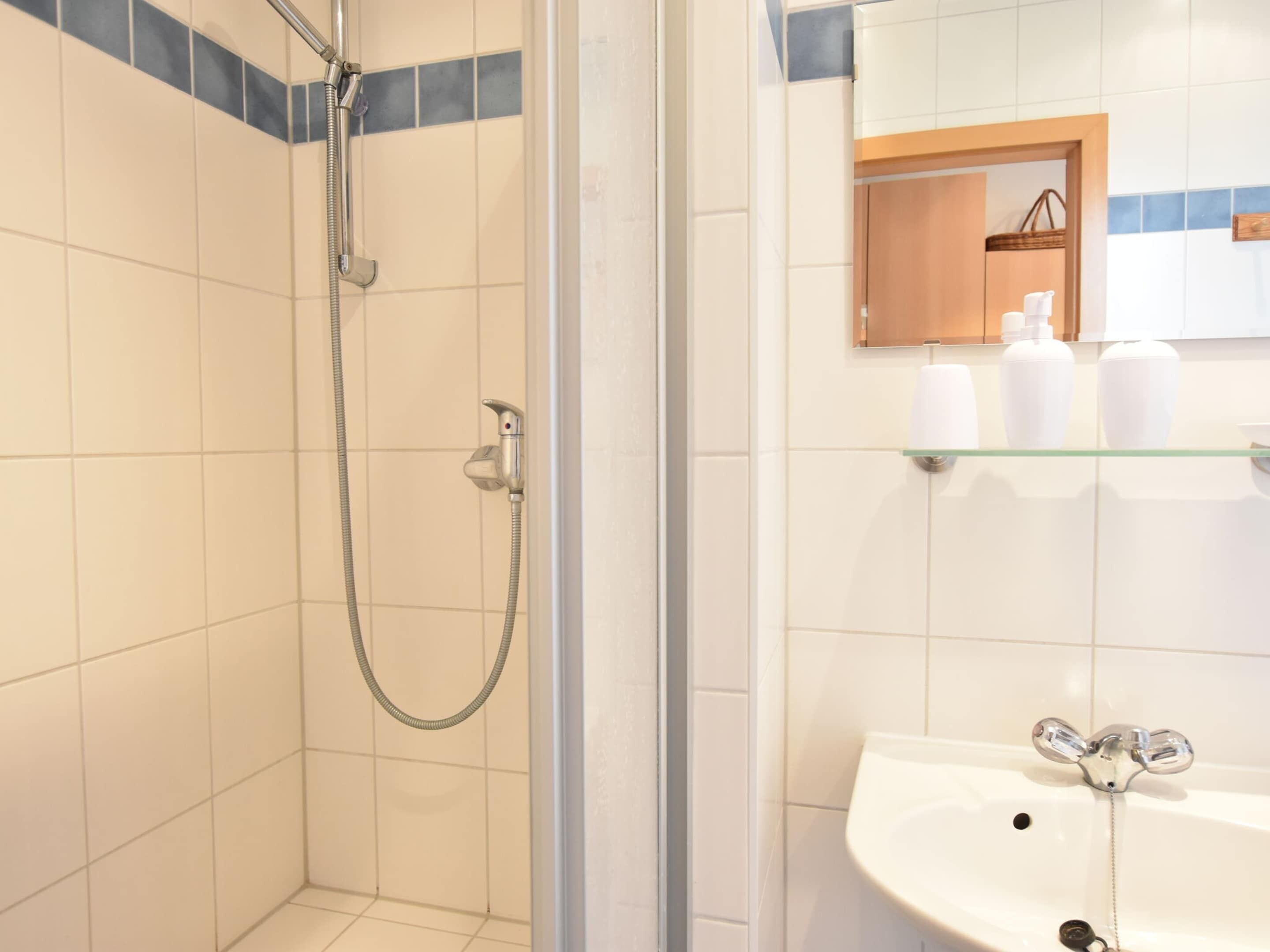 A bathroom with a shower, a sink, and a mirror.