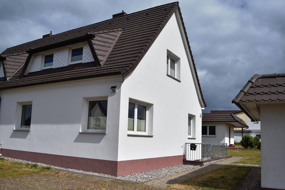 A modern two-story house with a sloped roof, multiple windows, and a small front porch.