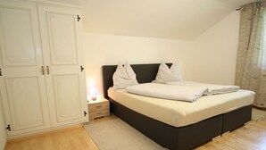 Ein Schlafzimmer mit Bett, Nachttisch, Kleiderschrank und einem Fenster mit Vorhängen.