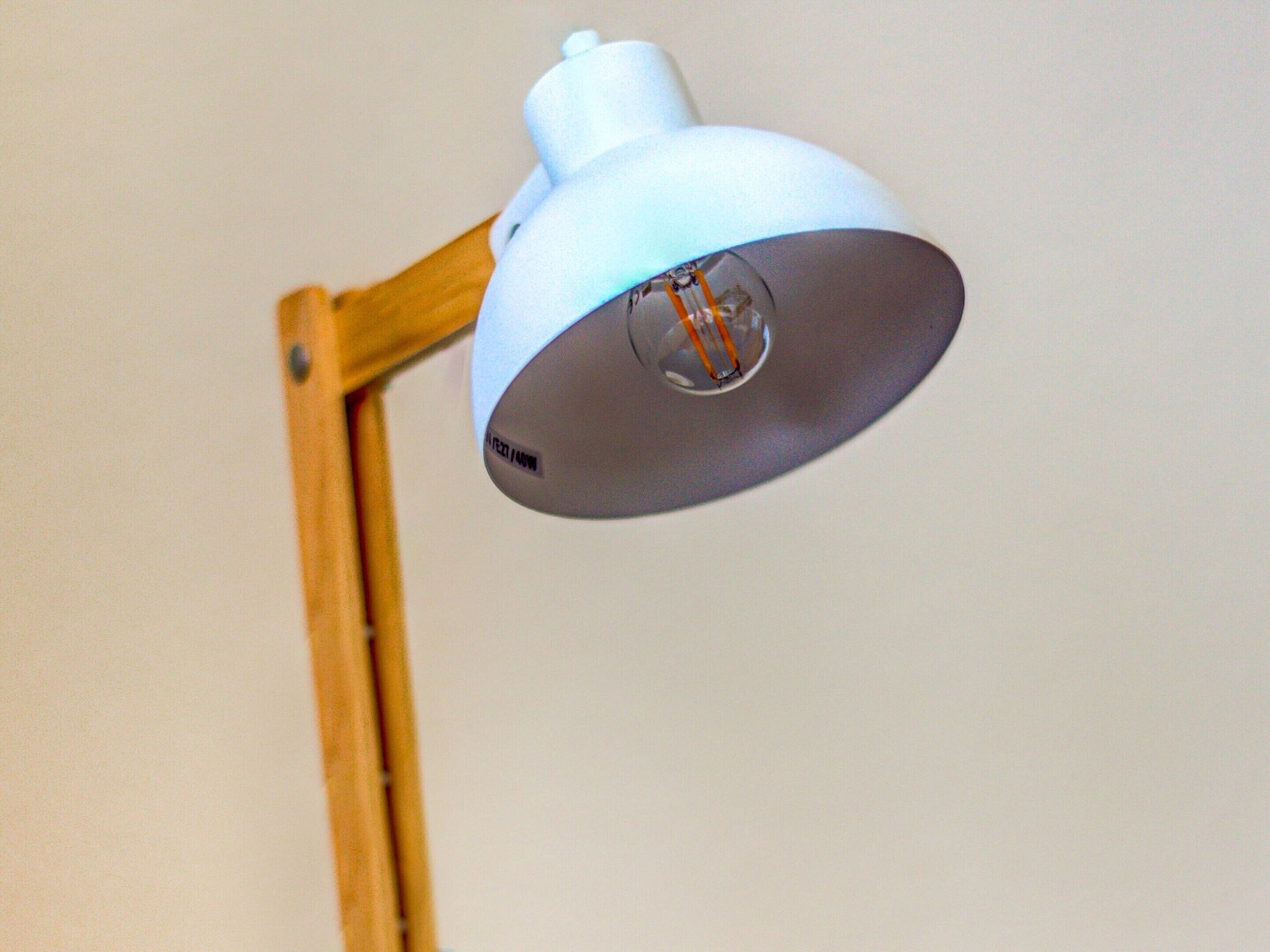 A white desk lamp with a clear glass shade and a wooden stand.
