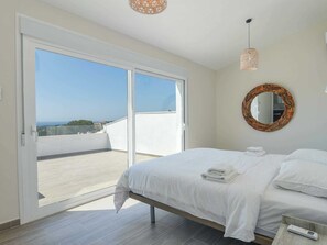 A bedroom with a bed, a round mirror, and a view of the sea through a sliding door. - Unique Villa in Moraira With Infinity Pool (Teulada)