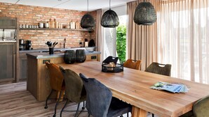 A modern kitchen with a brick wall, wooden beams, and pendant lights. - House With Sauna, Outdoor spa and Pedal Boat in Vlagtwedde (Vlagtwedde)