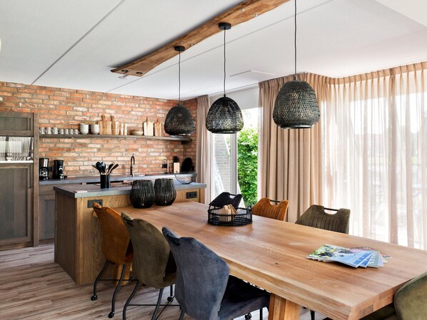 Une cuisine moderne avec un mur en briques, des poutres en bois et des luminaires suspendus.
