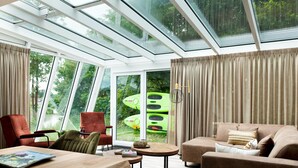 A modern living room with a glass ceiling, a sofa, chairs, a table, and a view of green boats. - House With Sauna, Outdoor spa and Pedal Boat in Vlagtwedde (Vlagtwedde)