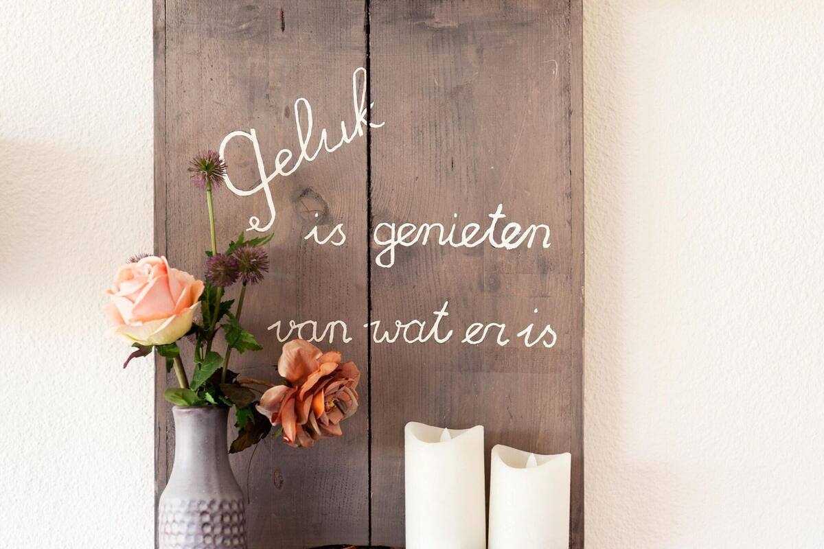 A wooden shelf with a vase of flowers and candles.