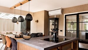 A modern kitchen with a large island, pendant lighting, and a view to the outside. - House With Sauna, Outdoor spa and Pedal Boat in Vlagtwedde (Vlagtwedde)