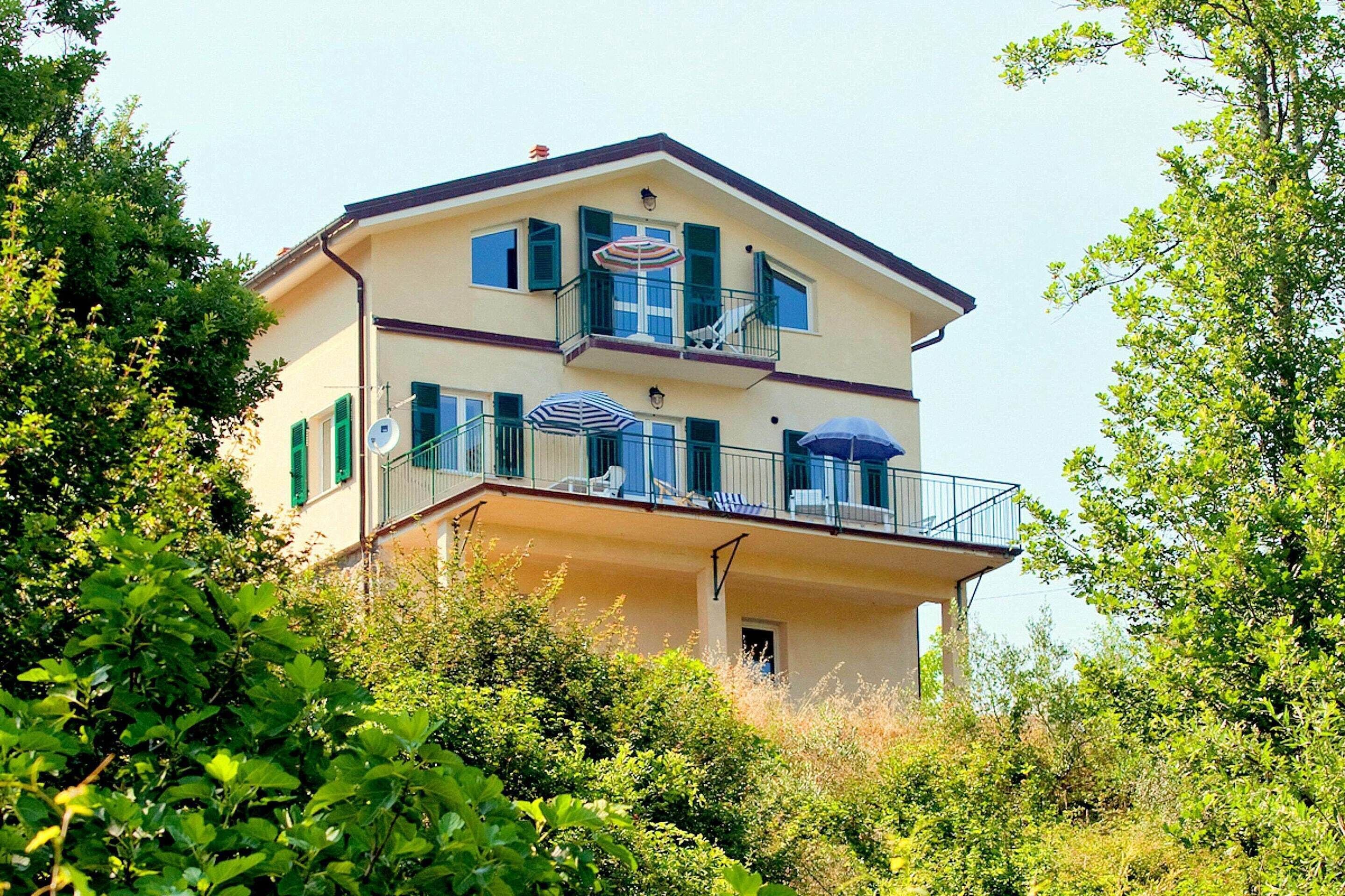 Een gebouw met twee verdiepingen en balkons, omringd door groen.
