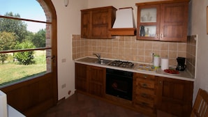 A kitchen with wooden cabinets, a gas stove, a dishwasher, and a window with a view of greenery.