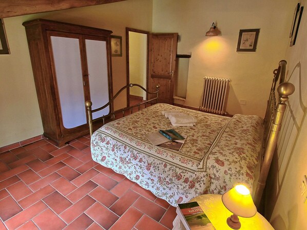 Une chambre à coucher avec un lit, une armoire en bois, un radiateur et une lampe.