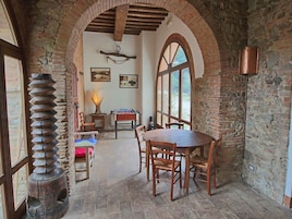 Uma área de refeições rústica com uma mesa e cadeiras de madeira, uma mesa de futebol de mesa e uma parede de pedra.