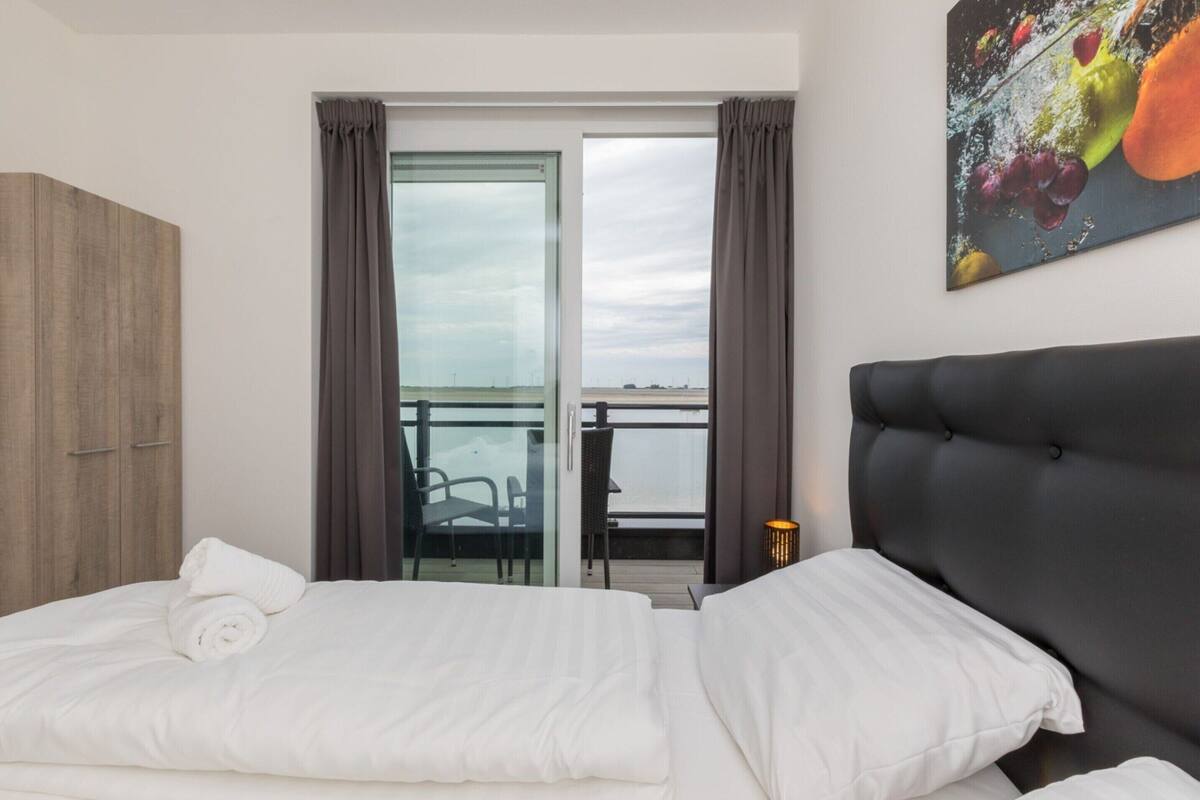 Une chambre d’hôtel avec un lit, un canapé, une fenêtre avec des rideaux, une chaise et une table.