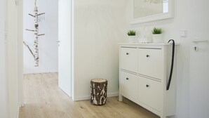 Um corredor com um guarda-roupa branco, uma pequena planta em cima e um candeeiro pendurado.