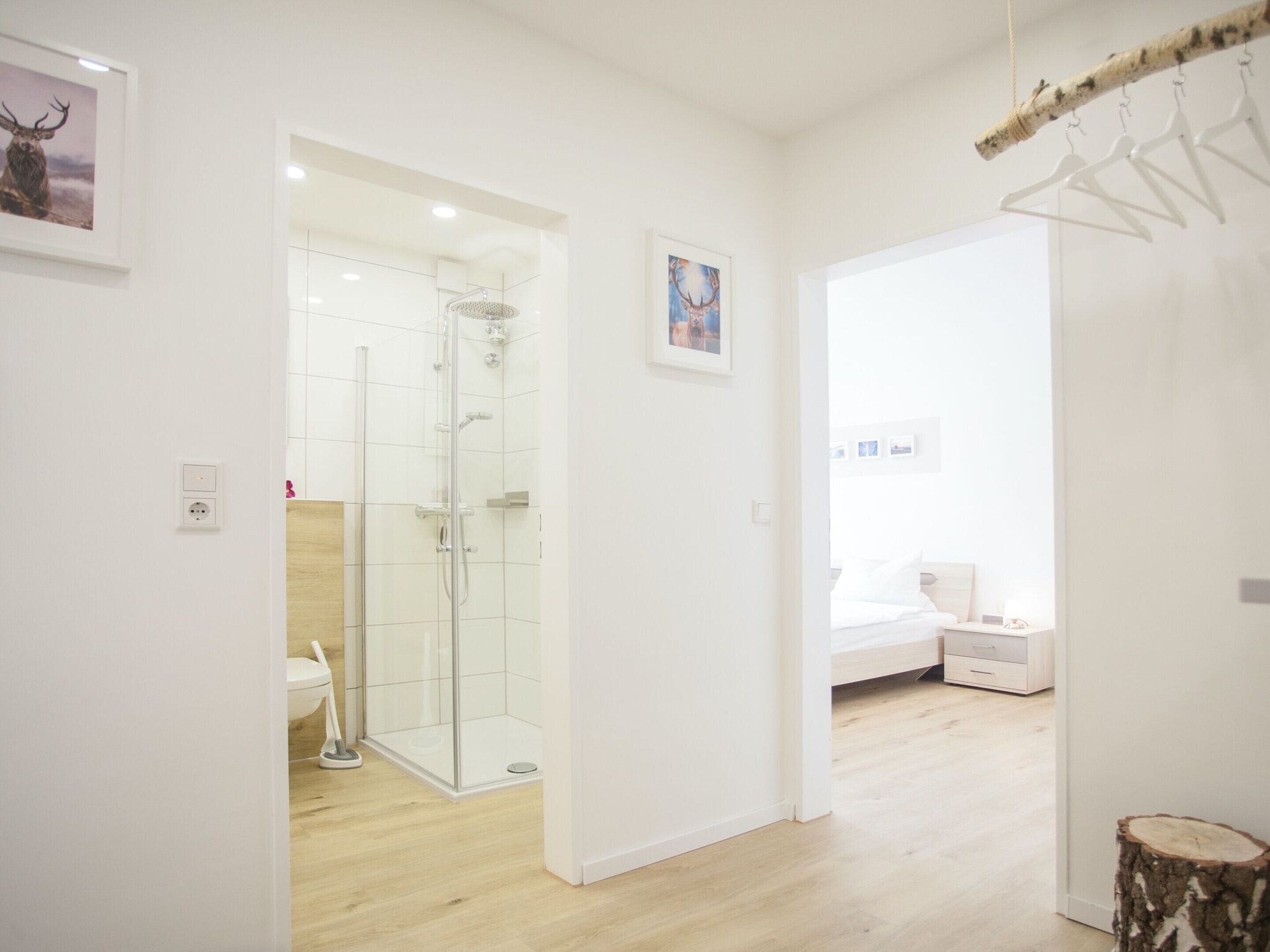 Une chambre d’hôtel moderne équipée d’une douche, d’un lit et d’un plancher en bois.