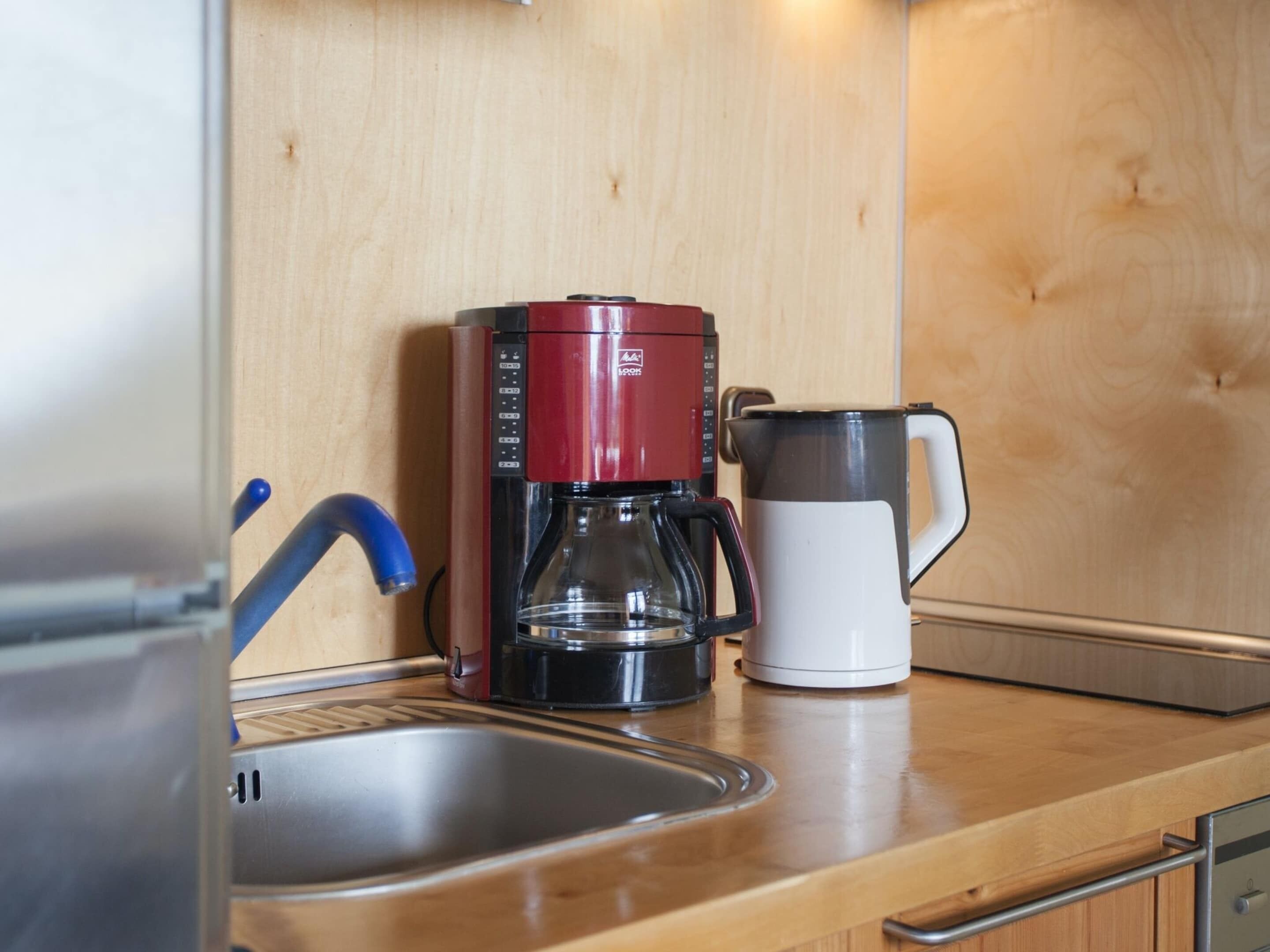 Una cocina con cafetera, hervidor y lavabo.