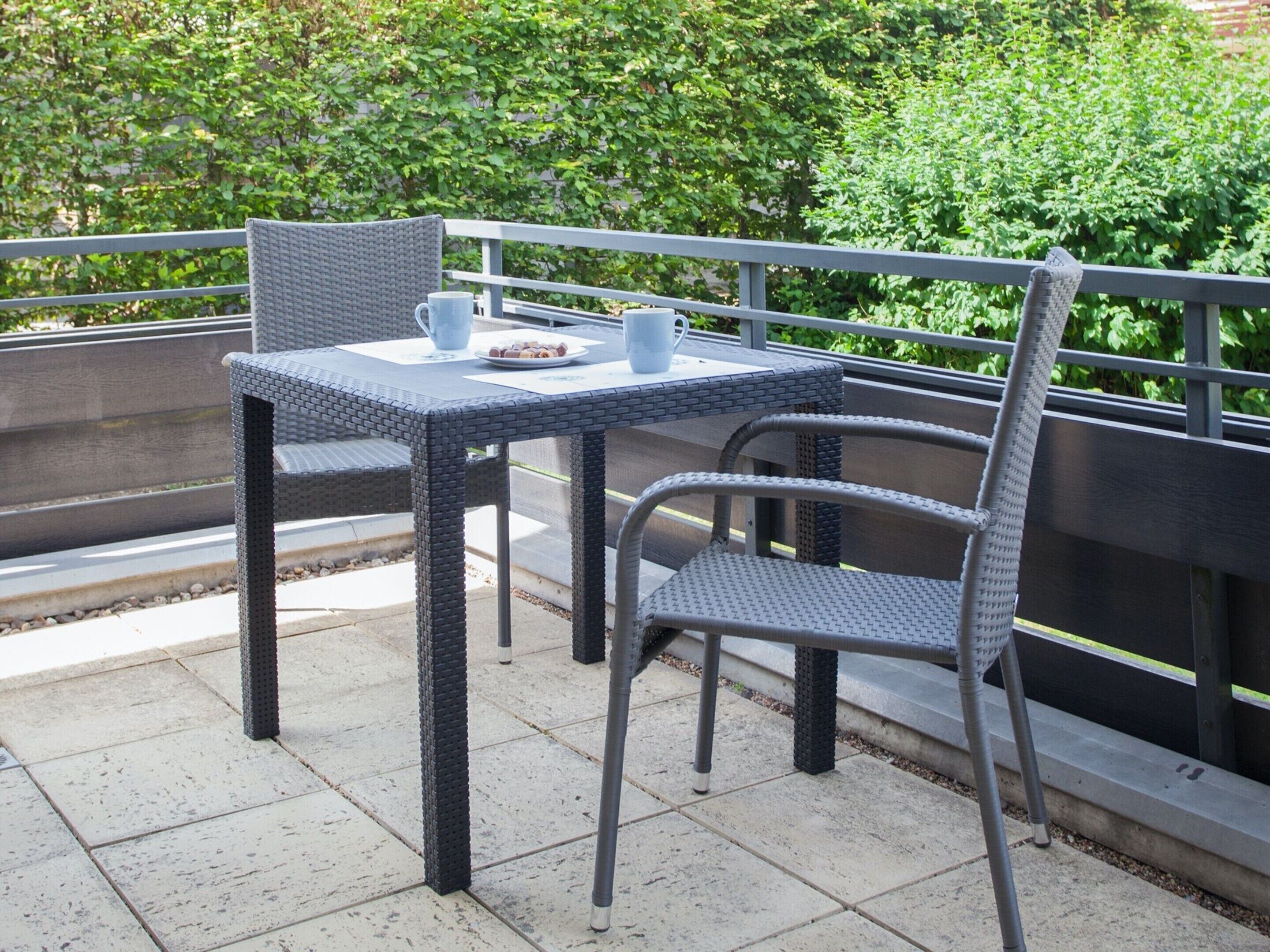 Un patio al aire libre con una mesa y dos sillas, una taza y un plato con comida.