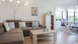 Uma sala de estar moderna com um sofá seccional marrom, uma mesa de centro de madeira e um espaço de jantar com mesa e cadeiras.