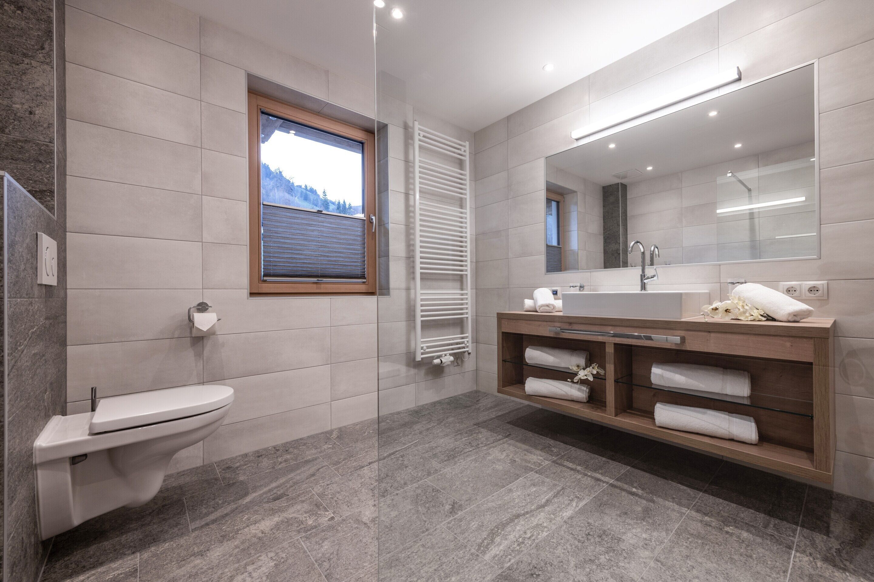 A modern bathroom with a toilet, sink, and large mirror.