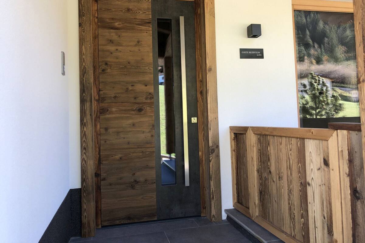 A wooden door with a glass panel, a sign reading 'GASTE RECEPTION,' and a framed picture on the wall.