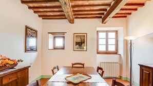 Une salle à manger avec une table en bois, des chaises, un radiateur et un lampadaire.