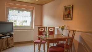 A dining area with a table, chairs, a television, and a window with a view of buildings. - Spacious Holiday Home in Ulmen Near the Centre (Ulmen)