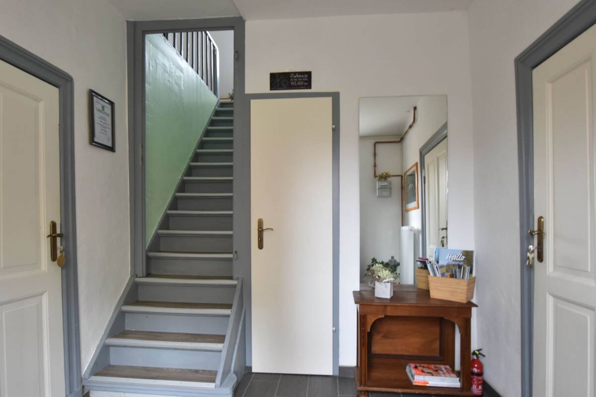 Un escalier menant à un palier où se trouve une porte sur laquelle est inscrit « Bienvenue ».