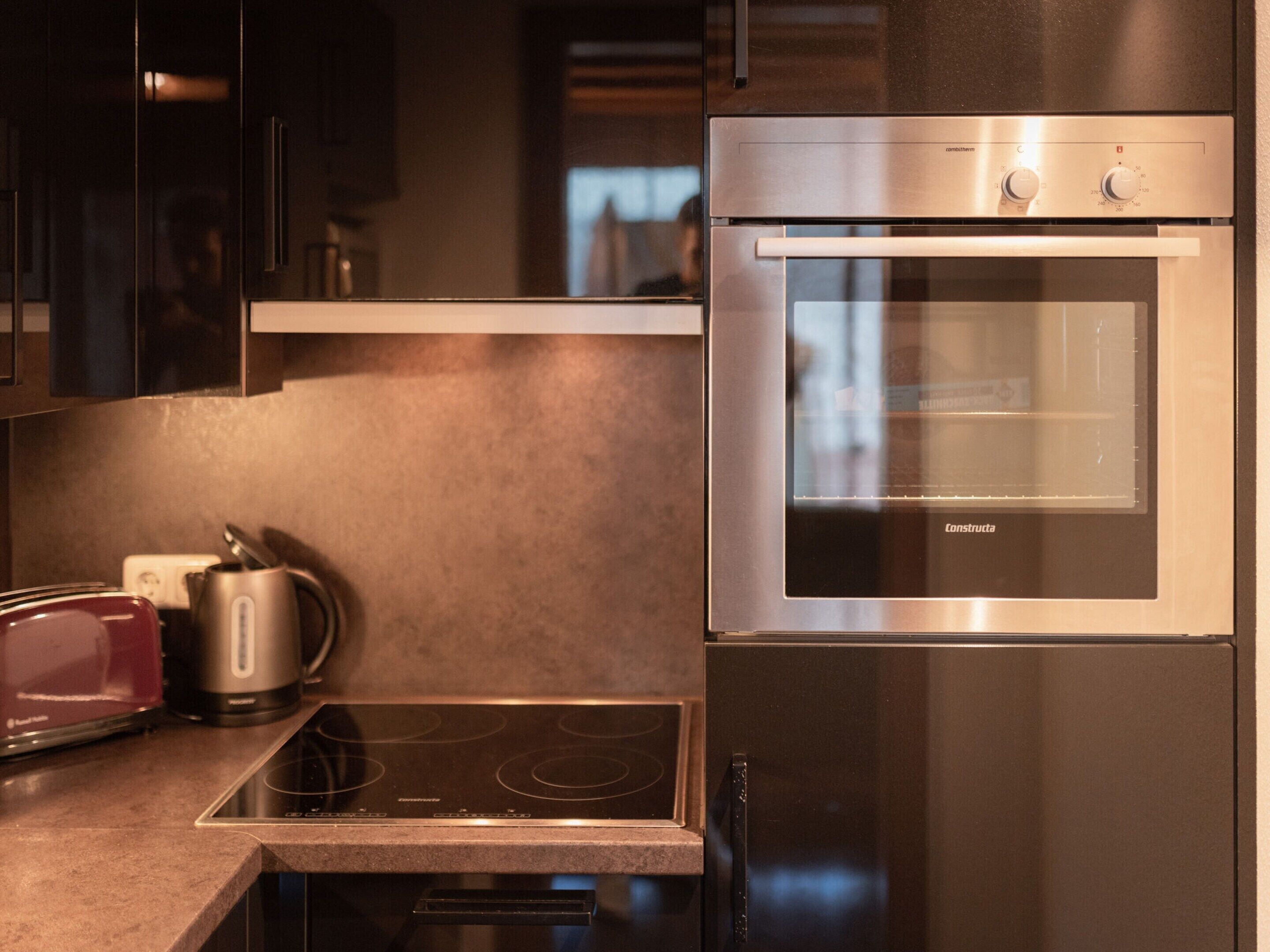 A modern kitchen with a built-in oven, a stovetop, and a kettle.