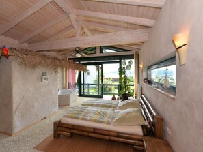 A bedroom with a large bed, a ceiling fan, a view of the outdoors, and a window with a sailboat model. - Tranquil Holiday Home in Blossersberg With Terrace (Viechtach)