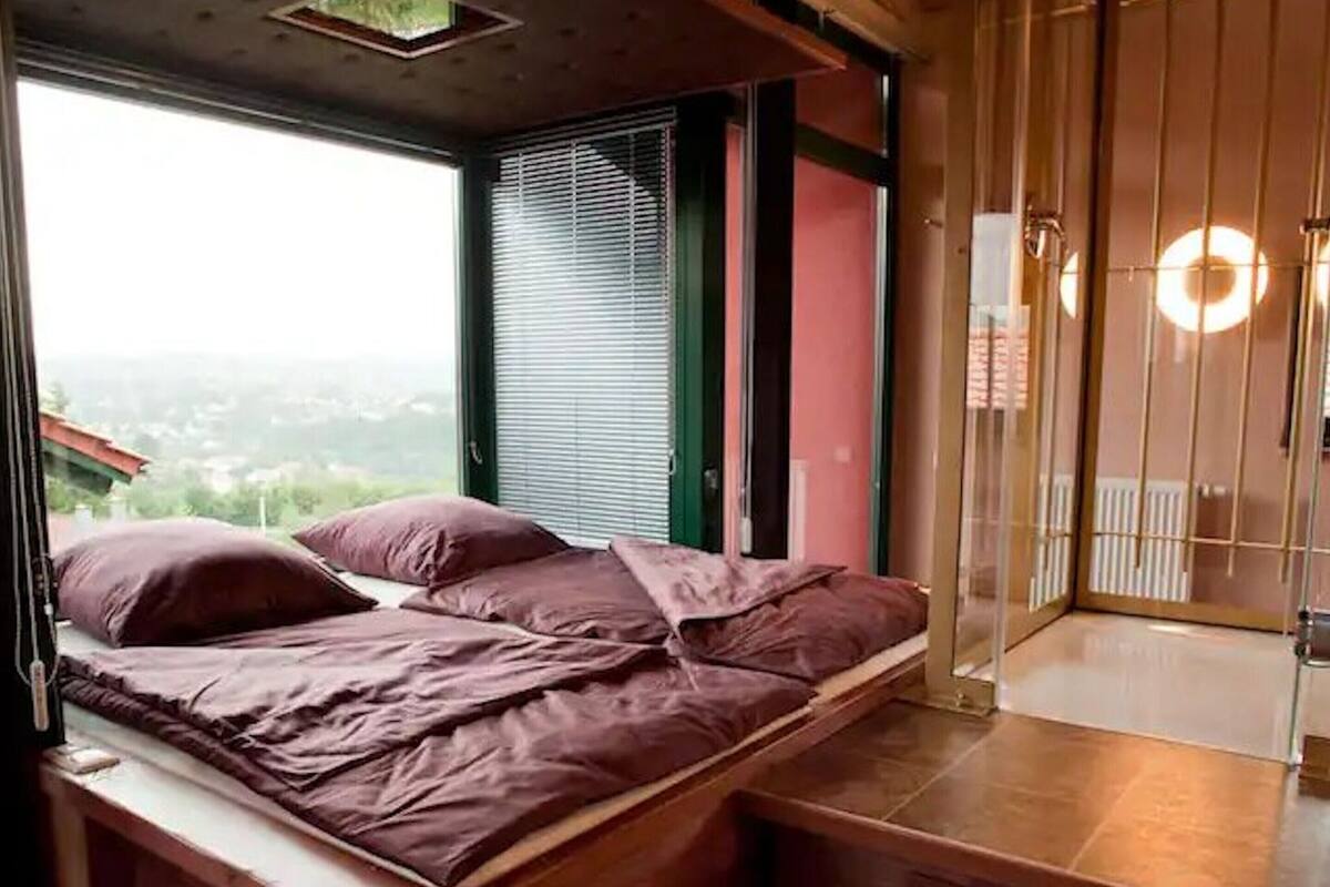 Ein Schlafzimmer mit einem Bett, einem Fenster und Blick ins Freie.