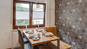 A dining area with a wooden table set for four, a window with blinds, and a patterned wallpaper on the adjacent wall. - Pretty Apartment in Medebach With Adjacent Forest (Medebach)