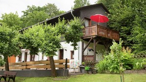 A two-story house with a balcony, surrounded by greenery and a wooden fence. - Pretty Apartment in Medebach With Adjacent Forest (Medebach)