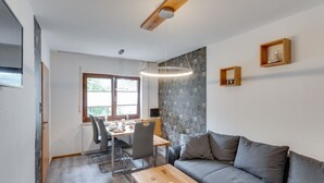 A modern living room with a grey sofa, a wooden coffee table, and a dining area with a table and chairs. - Pretty Apartment in Medebach With Adjacent Forest (Medebach)