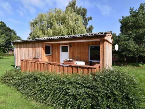 Une cabane en bois dotée d’un balcon, d’une porte et de fenêtres.