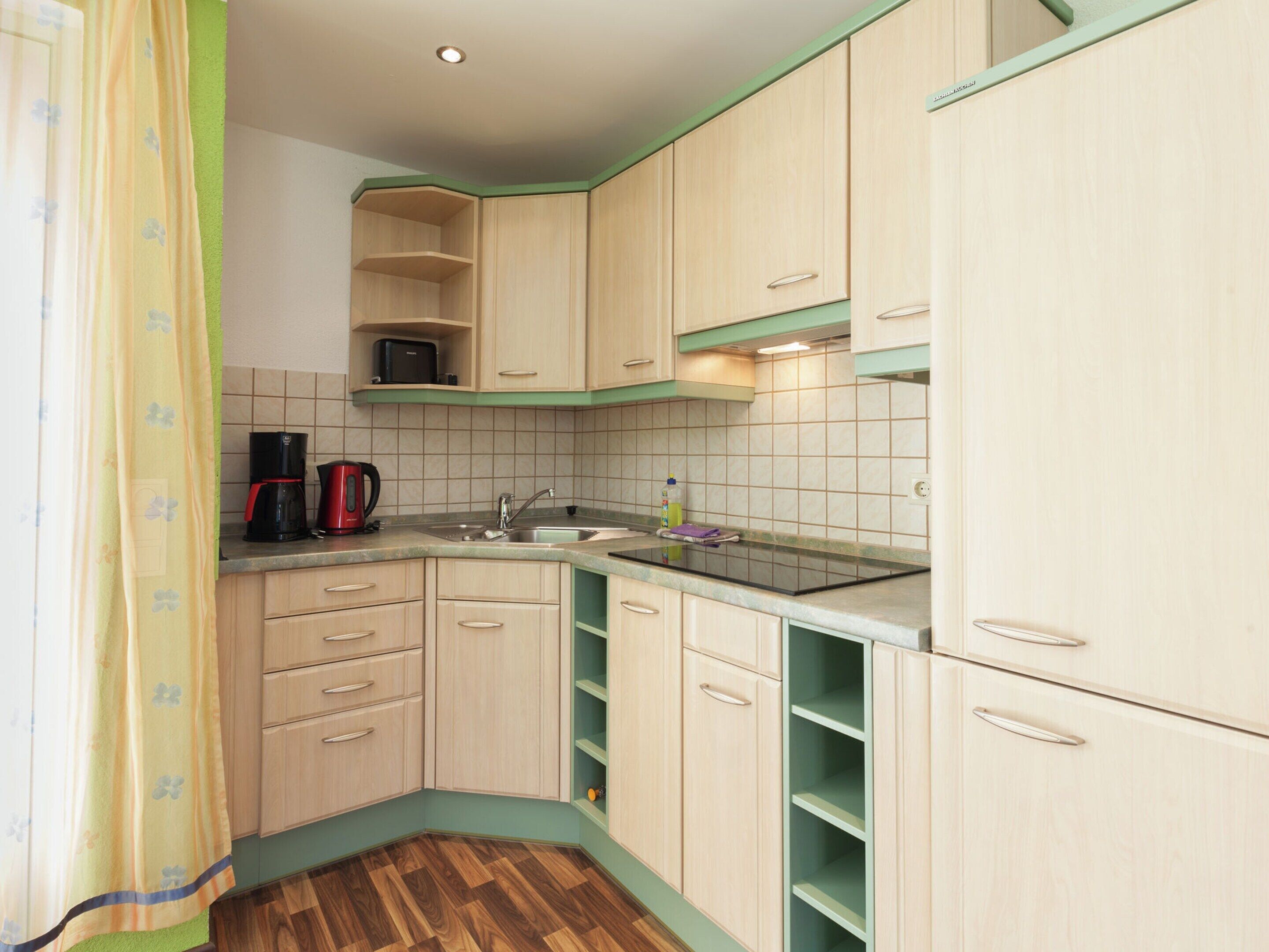 A compact kitchen with light wooden cabinets, a sink, and a coffee maker.