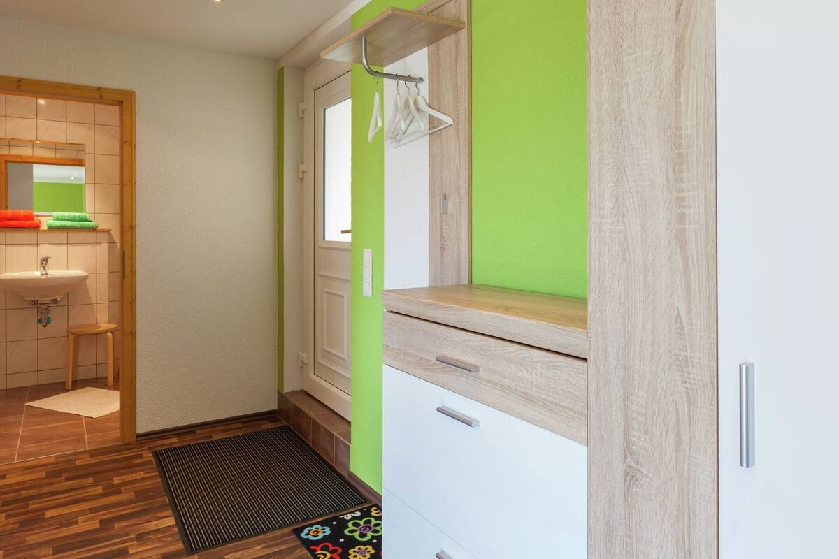 A modern bathroom with a wooden vanity, a sink, and a green accent wall.