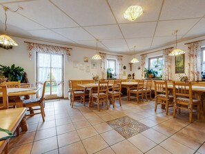 A dining area with wooden tables and chairs, a patterned tile floor, and hanging pendant lights. - Spacious Apartment With Sauna in Schonsee (Schoensee)