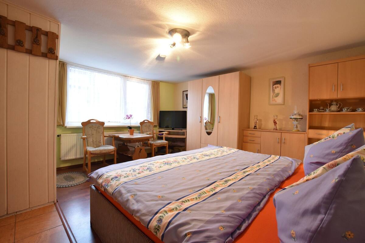 Une chambre à coucher comprenant un lit, un bureau, une chaise, une télévision et une armoire.