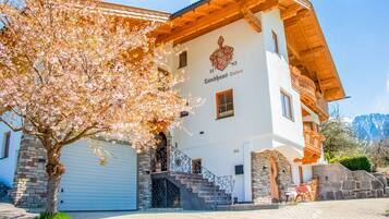 A traditional chalet with a stone facade, a wooden balcony, and a garage.
