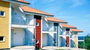 Un hotel moderno de varios pisos con balcones y una vista despejada del mar.
