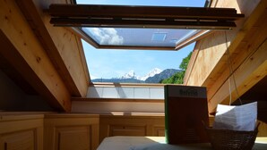A room with a skylight, wooden beams, a table, a basket with papers, and a sign reading "Belvilla".