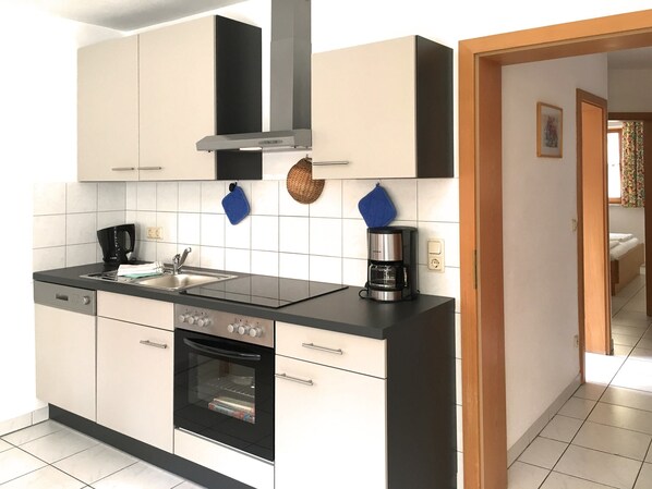 A modern kitchen with a built-in oven, a coffee maker, and a sink.
