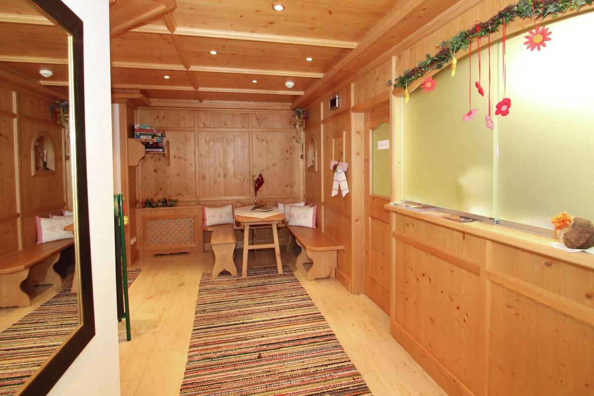 A wooden interior with a bench, a table, and a window with decorations.