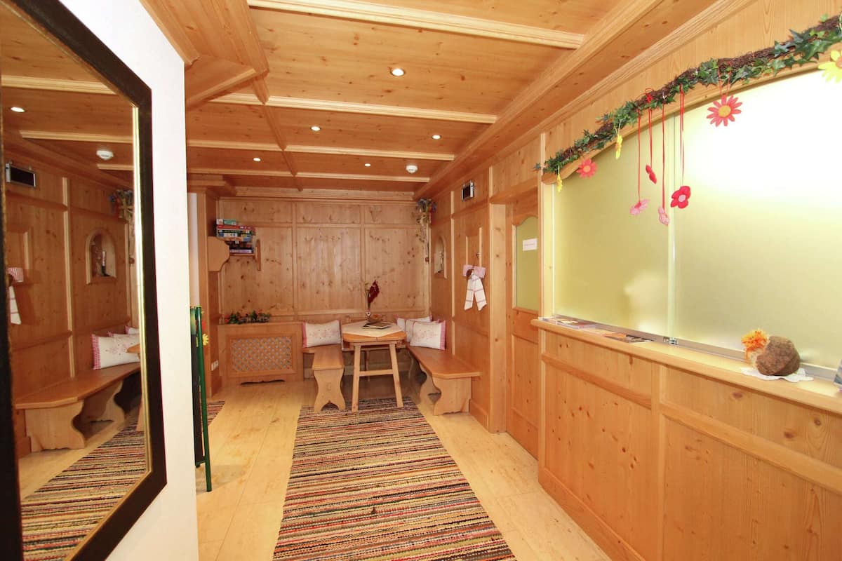 Un interior de madera con un banco, una mesa y una ventana con adornos.