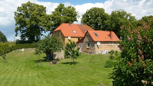 Ein zweistöckiges Haus mit rotem Ziegeldach, umgeben von einem gepflegten Rasen und Bäumen.