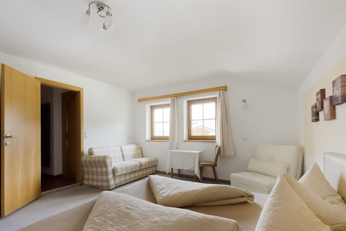 A room with a bed, a sofa, a chair, and a small table.