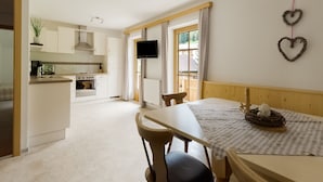 A modern kitchen with white cabinets, a dining table with a checkered tablecloth, and a TV mounted on the wall. - Lovely Apartment in Hainzenberg Next to Forest (Hainzenberg)