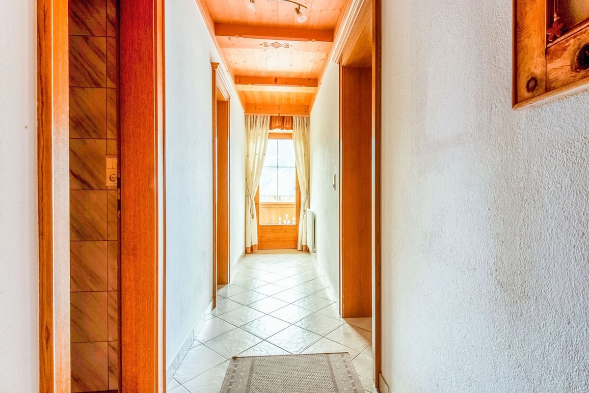 A hallway with wooden floors, white walls, and a ceiling with exposed beams.