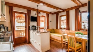 A compact kitchen with wooden beams, a built-in microwave, and a dining area with a wooden table and chairs. - Lovely Apartment in Hainzenberg Next to Forest (Hainzenberg)