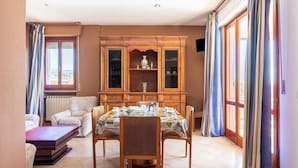 A dining area with a wooden cabinet, a table set for four, and a sofa. - Nice Apartment in Tuoro sul Trasimeno With Pool (Tuoro sul Trasimeno)